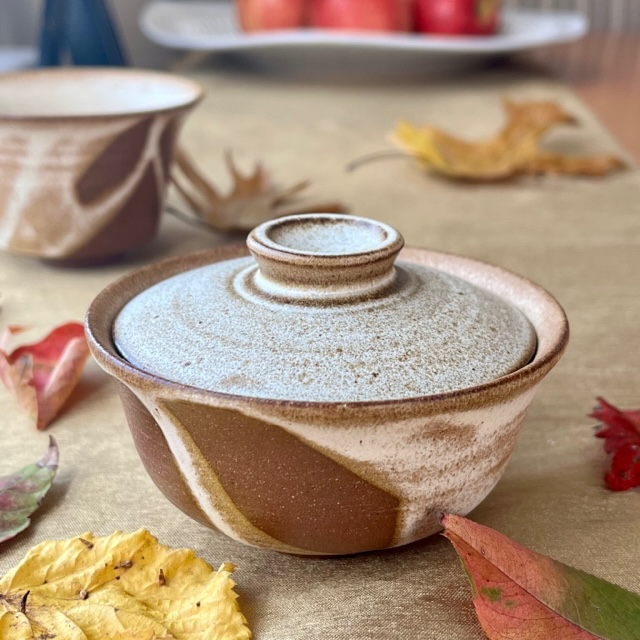 Story of a Teacup image: brown and cream gaiwan with matching teacup in the bckground on a table with fall leaves
