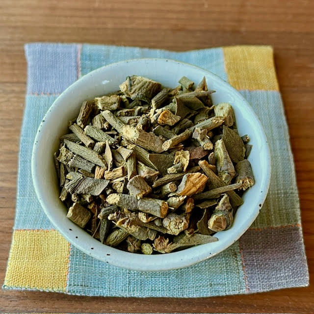 Mistletoe herbal tea--looks like tiny chopped branches of wood--sitting on a Korean coaster.