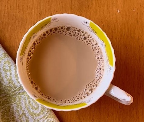Cup of tea--masala chai--in a white and yellow tecup.