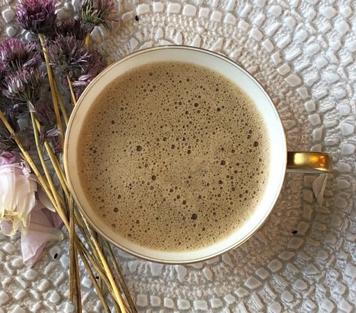 Valentine's tea: frothy Black Matcha next to decorative dried chives and peony petals