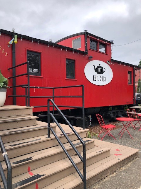 Steps by a bright red train caboose with the Tea Chai Te logo in black and white.