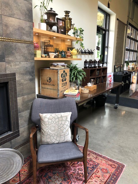 Inside Smith Teamaker on SE Washington St. Part of a stone fireplace, a gray chair with a pillow, and shelves of teaware.