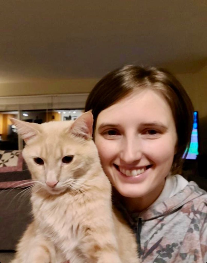 Michell Hovey, smiling and holding an orange cat.
