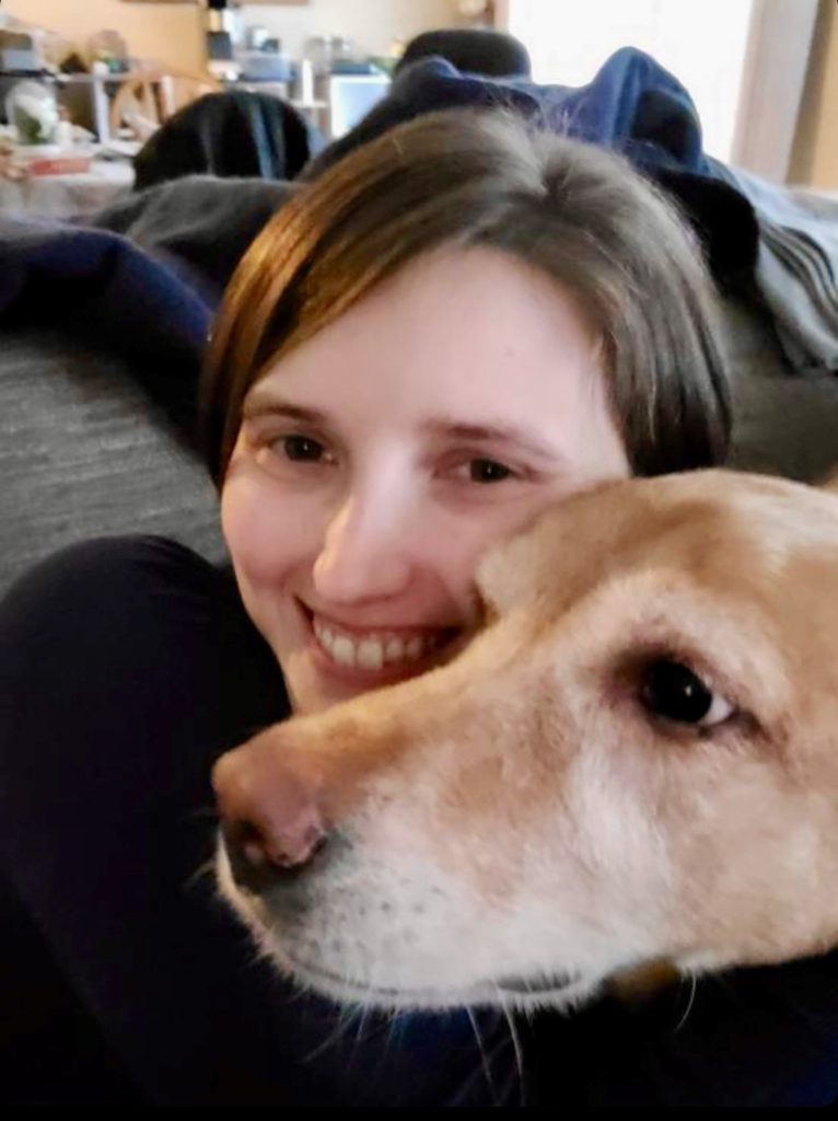 MIchell Hovey, smiling next to the face of her dog.
