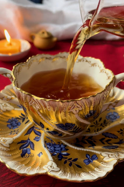 Colorful gold and blue teacup and saucer on vibrant red cloth