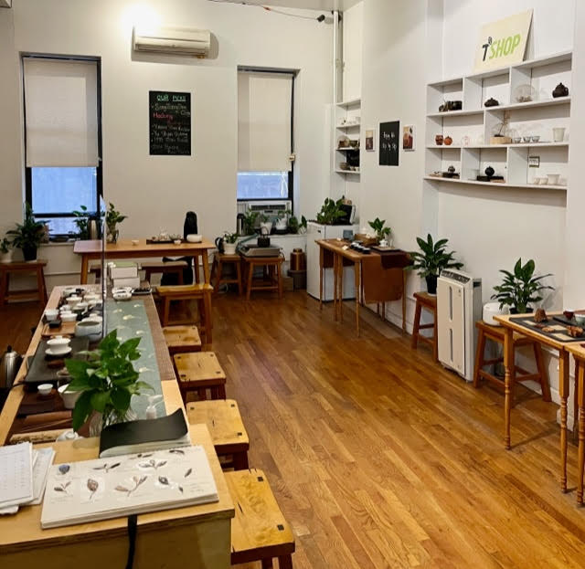 Inside T-Shop: their tea counter with wooden stools, the table you can reserve in the back, lots of ivy plants, and shelves and tables with teaware.