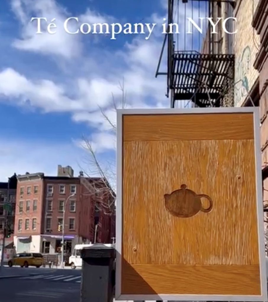 Wooden sign featuring silhouette of a teapot. Té in Manhattan puts the sign out only when they are open.