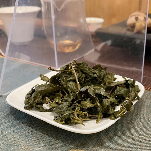 Li Shan Reserve tea leaves from T Shop after several infusions. The leaves are green, include some stems, and look open.