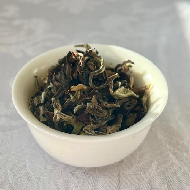 Indian Cloud tea leaves--brown and grown, slightly twisted--in a white teacup.
