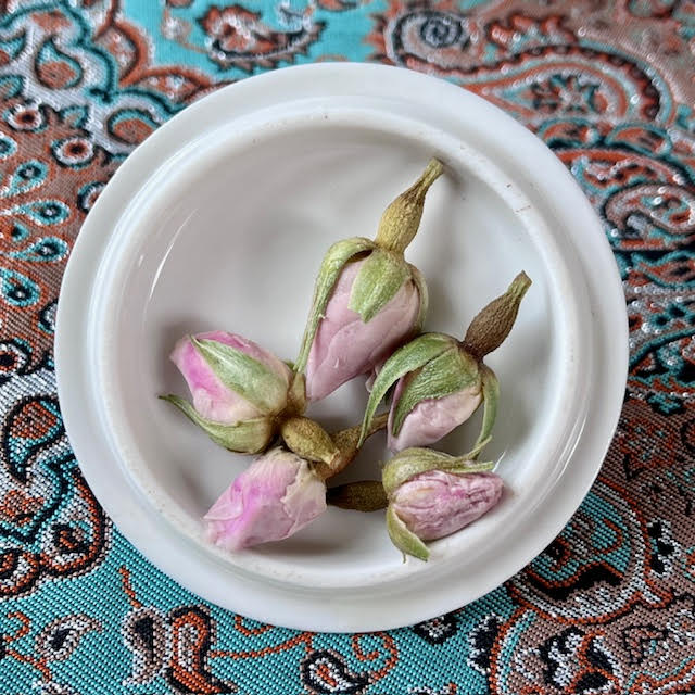 Steeped pink rosebuds on the white lid of a tea cupping set