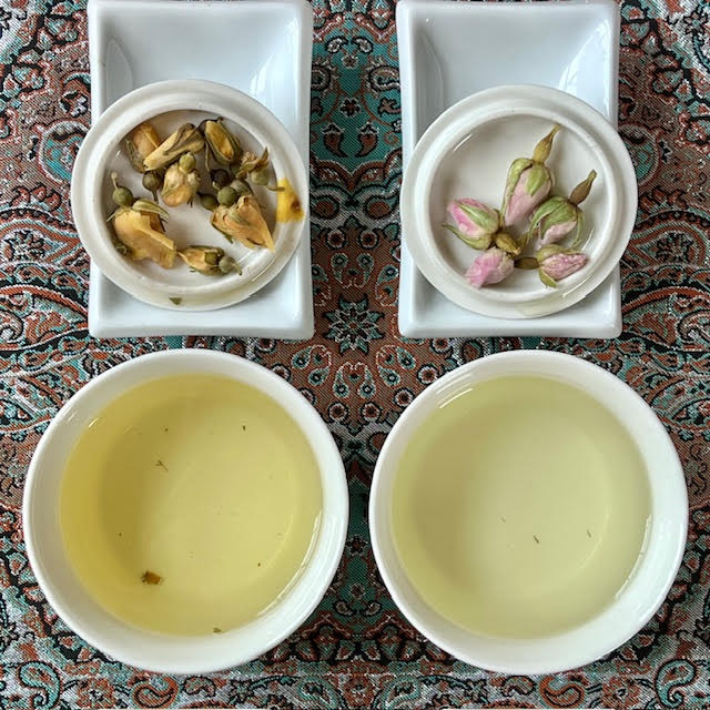 Steeped yellow and pink rosebuds and rosebud tea infusions in white cups