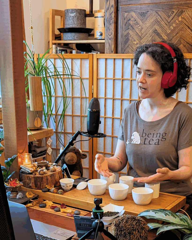 Sooz Hammond, wearing a Being Tea t-shirt, and teaching at their tea table.