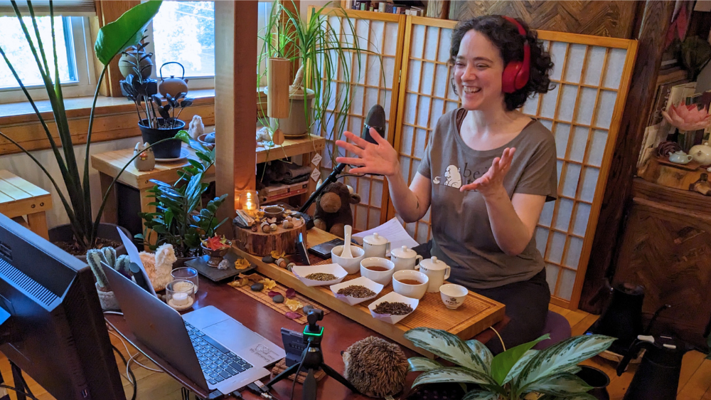 Sooz Hammond of Being Tea wearing red headphones in a tea studio with tea tasting equipment as part of the Tea Teacher Training