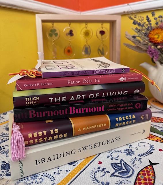 Stack of books showing some of the many that influenced Traci to push back against "my week ran me." Next to the book is a white clay teapot with dried flowers.