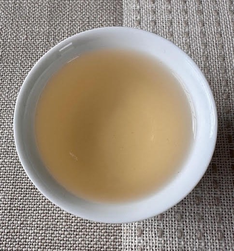 Chinese yellow tea--pale golden--in a white, handless teacup