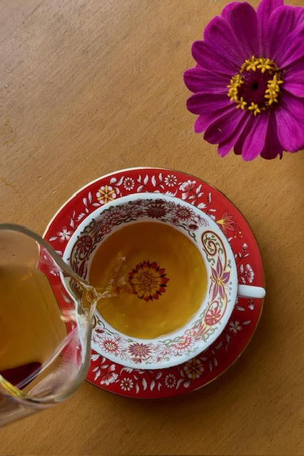 Pouring Rose Label Gold black tea into a red and white teacup with a floral pattern