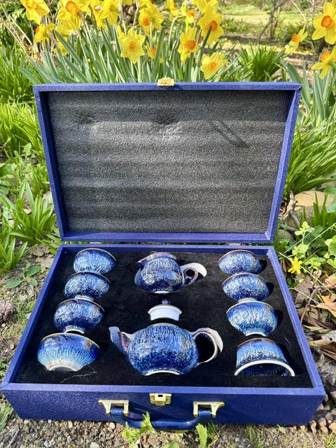 All the teaware inside the Umi Tea Sets Starry Sky Tea Set inside the blue giftbox with a handle. Yellow daffodils are in the background
