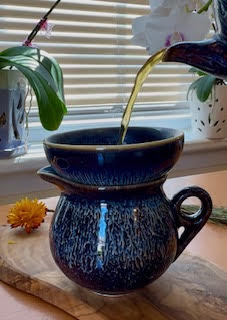 Pouring tea from the Starry Sky teapot from Umi Tea Sets through the ceramic and metal strainer into the fairness cup