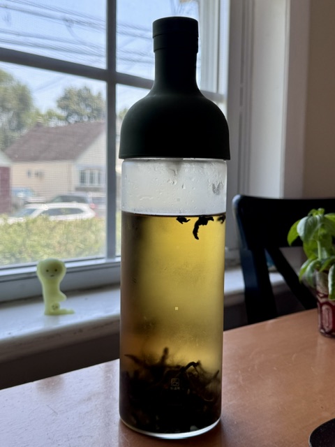 cold brew iced tea in a glass bottle with a green silicone top after steeping