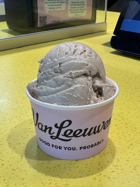 Medium brown, Early Grey tea ice cream at Van Leeuwen sitting in a cup that says "Van Leeuwen" on their yellow countertop