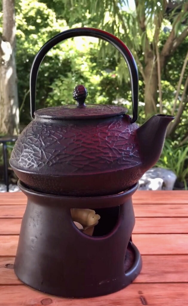 black iron tea kettle on a stand in a garden